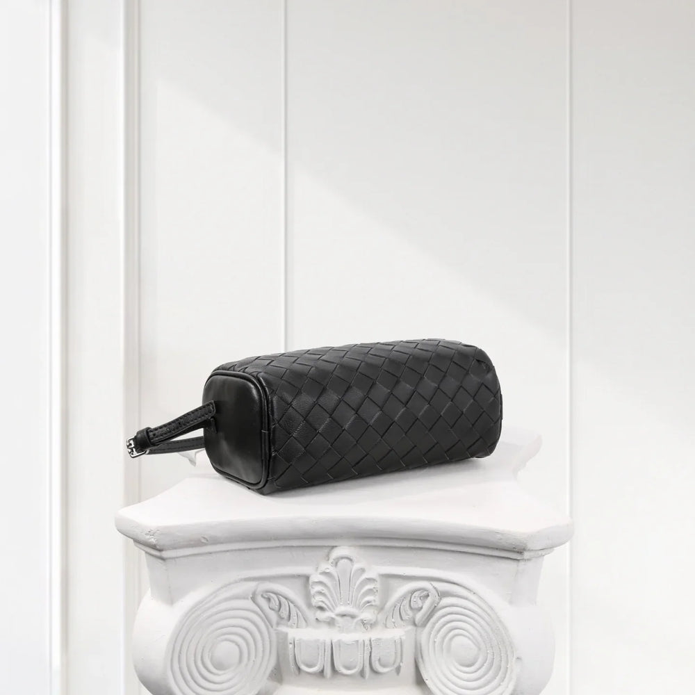 Black lambskin leather woven mini Boston bag with boxy shape on white ornate pedestal