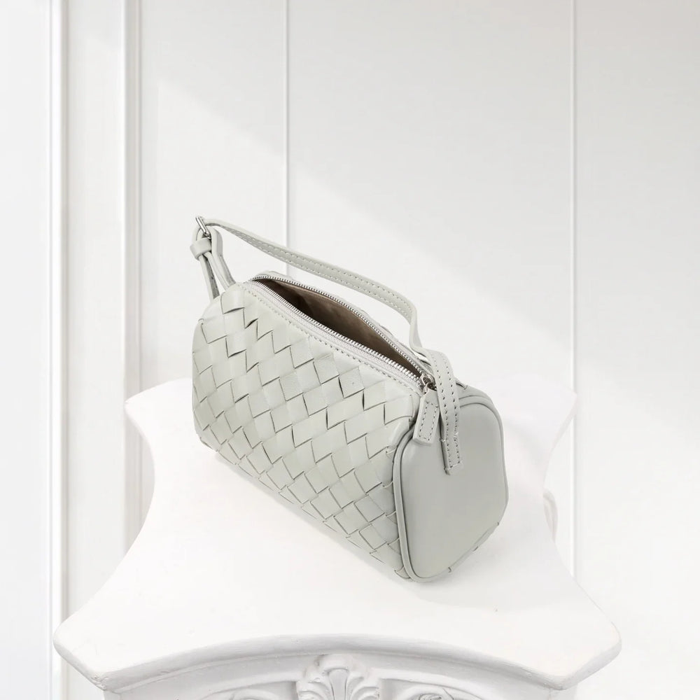 Mini woven lambskin leather crossbody bag with top handle in light grey on white pedestal.