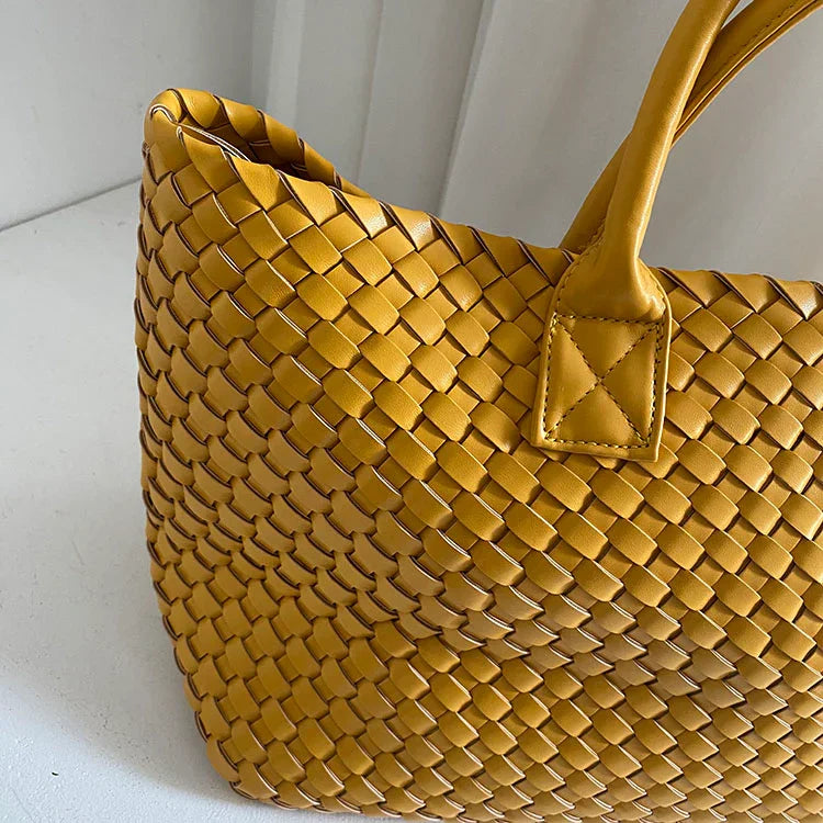 Large woven vegan leather tote bag in mustard yellow with double handles on white background