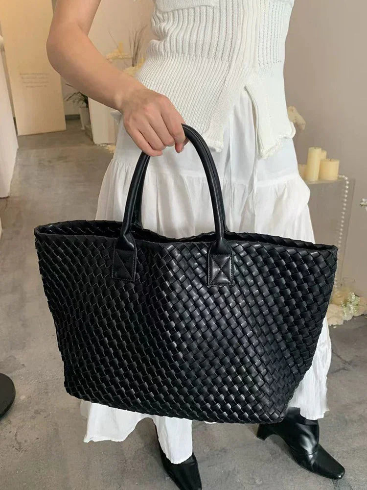 Woman carrying large black handwoven vegan leather tote bag with dual handles
