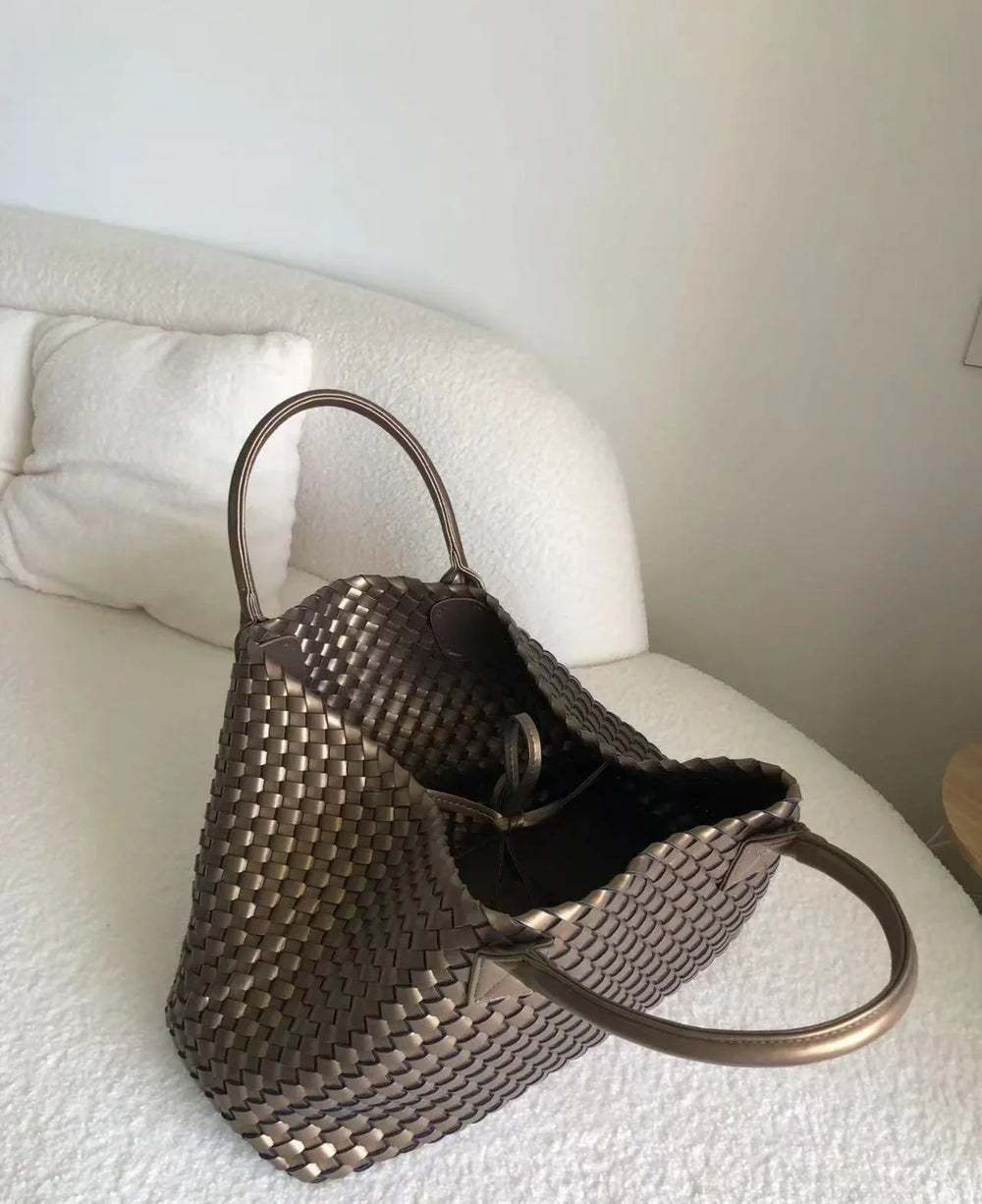 Large handwoven vegan leather tote bag with double handles on a white couch