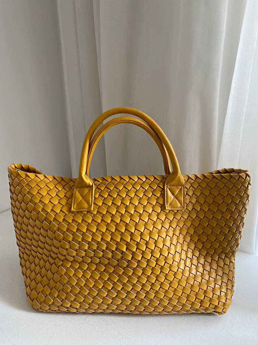 Large handwoven vegan leather tote bag in mustard yellow with double handles, against a white background