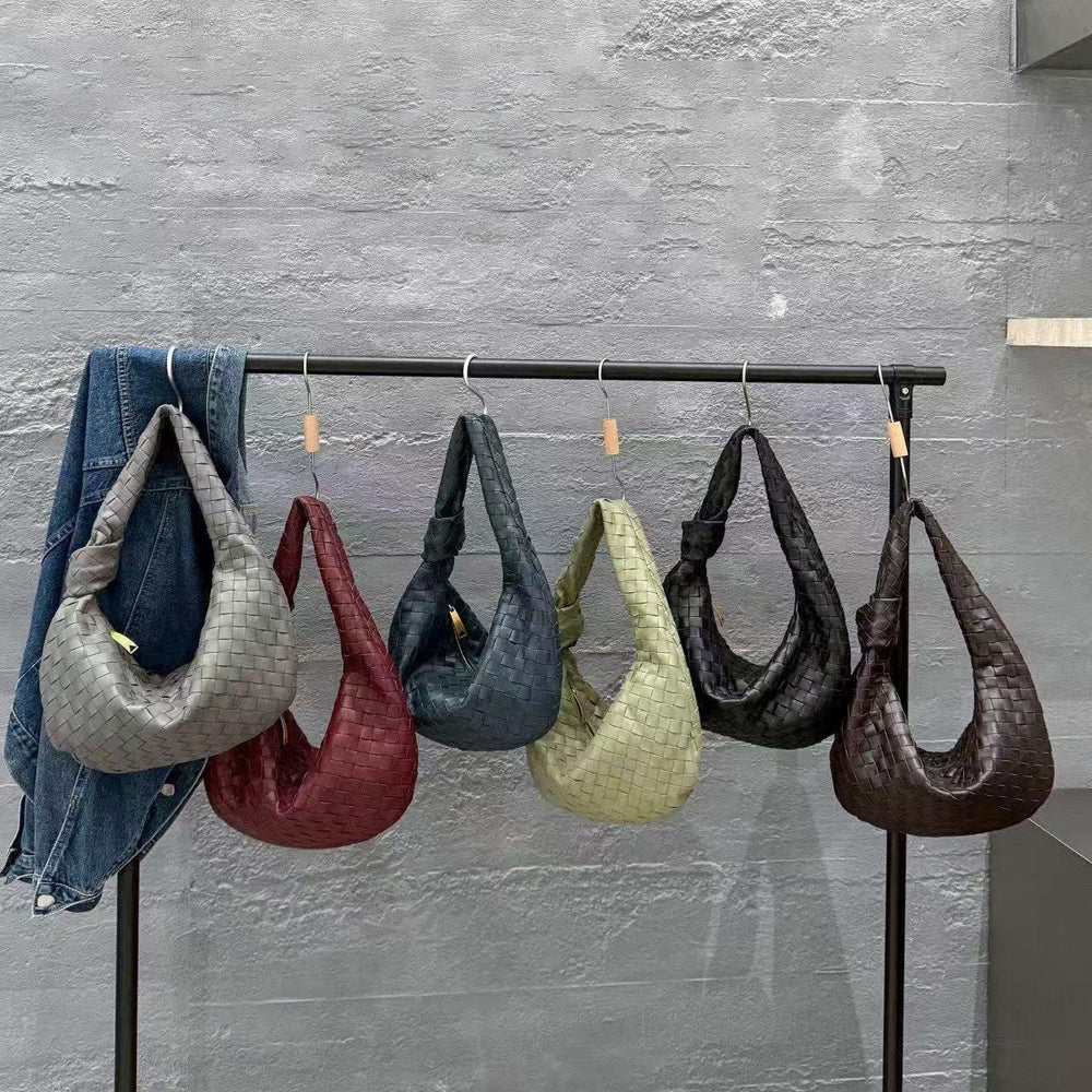 Five woven lambskin leather knotted handbags in assorted colors hanging on a clothing rack.
