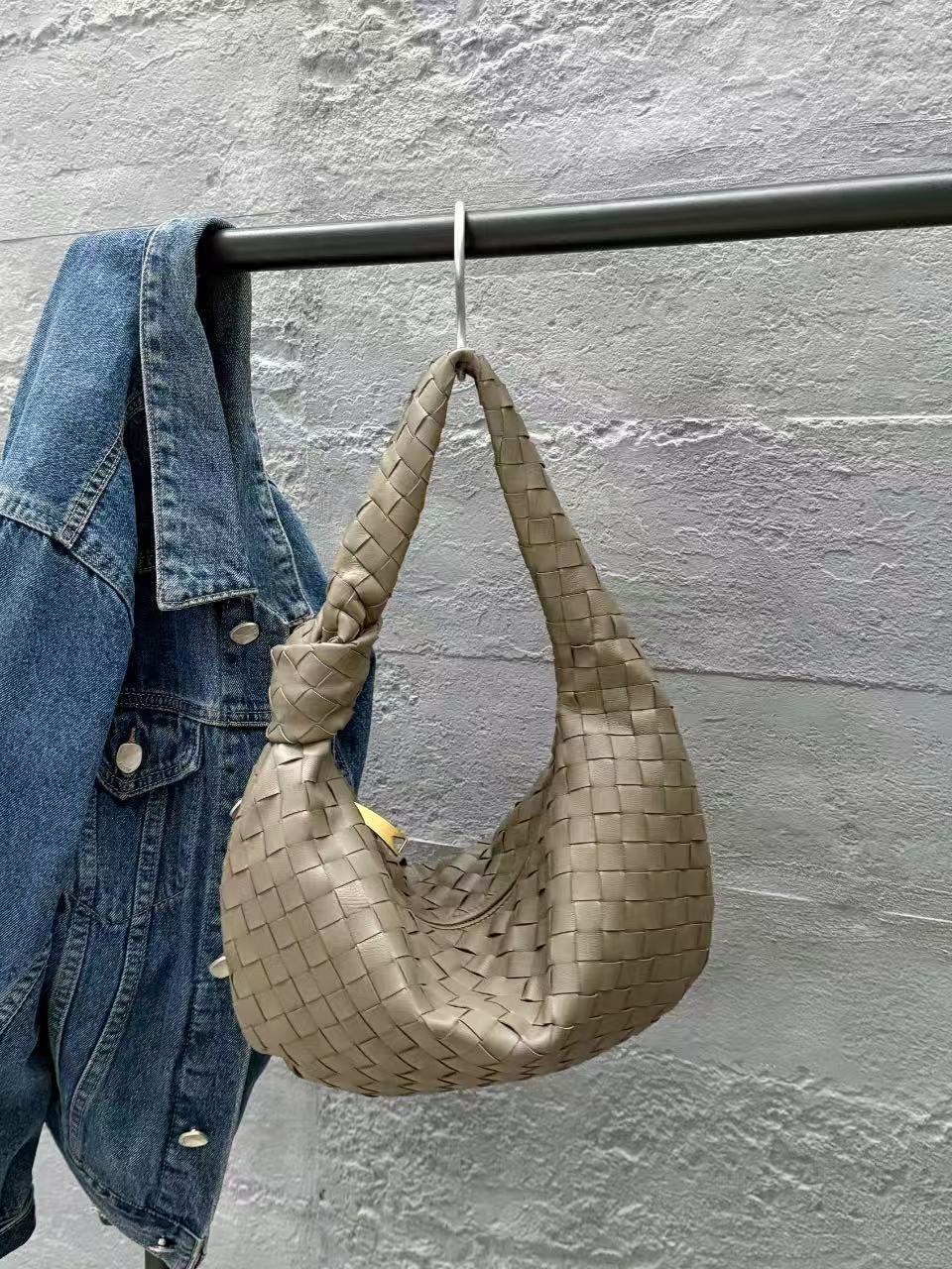 Taupe woven lambskin leather knotted handbag hanging beside a blue denim jacket