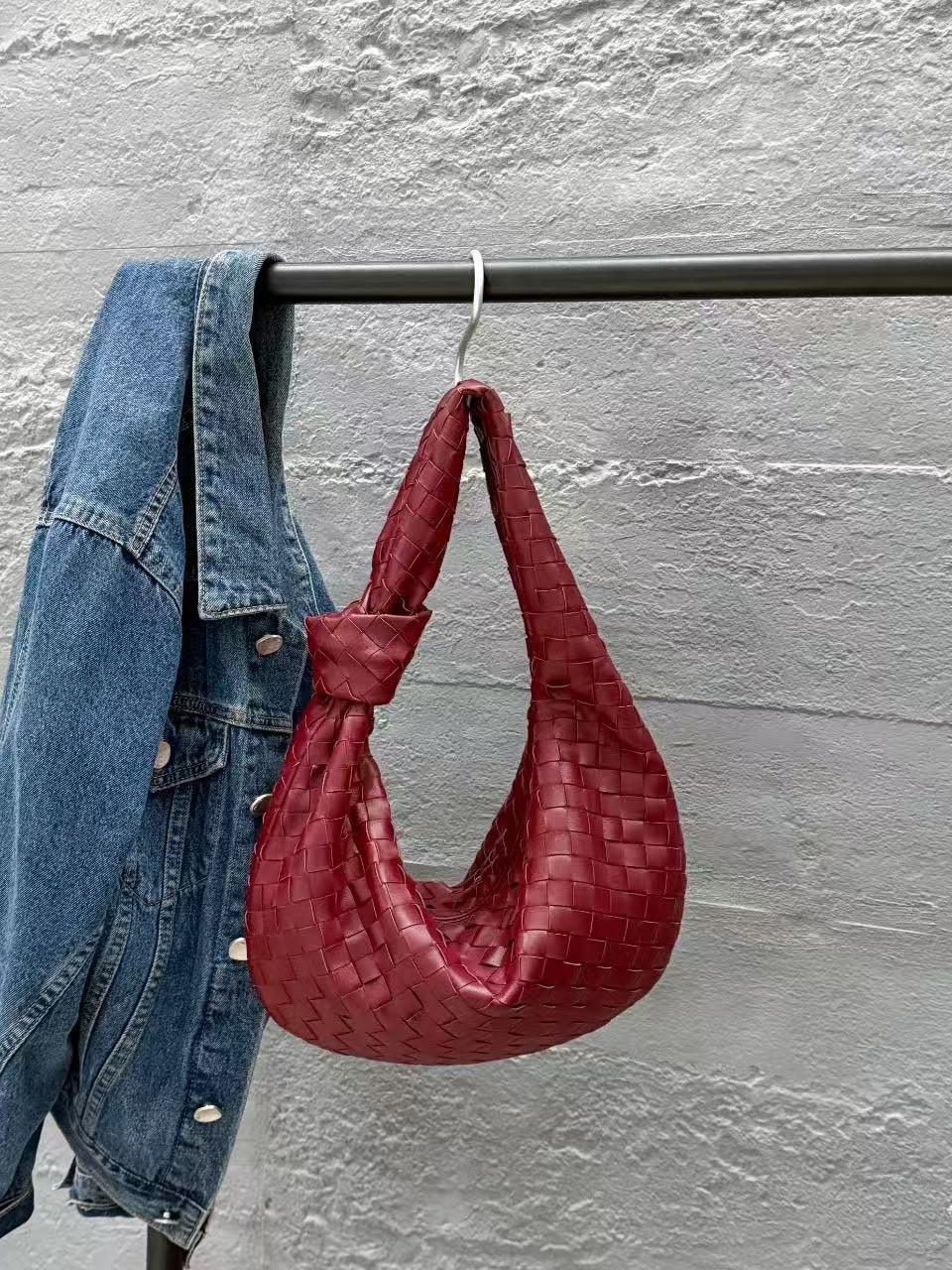 Red lambskin leather knotted handbag with intrecciato weave, hanging beside denim jacket
