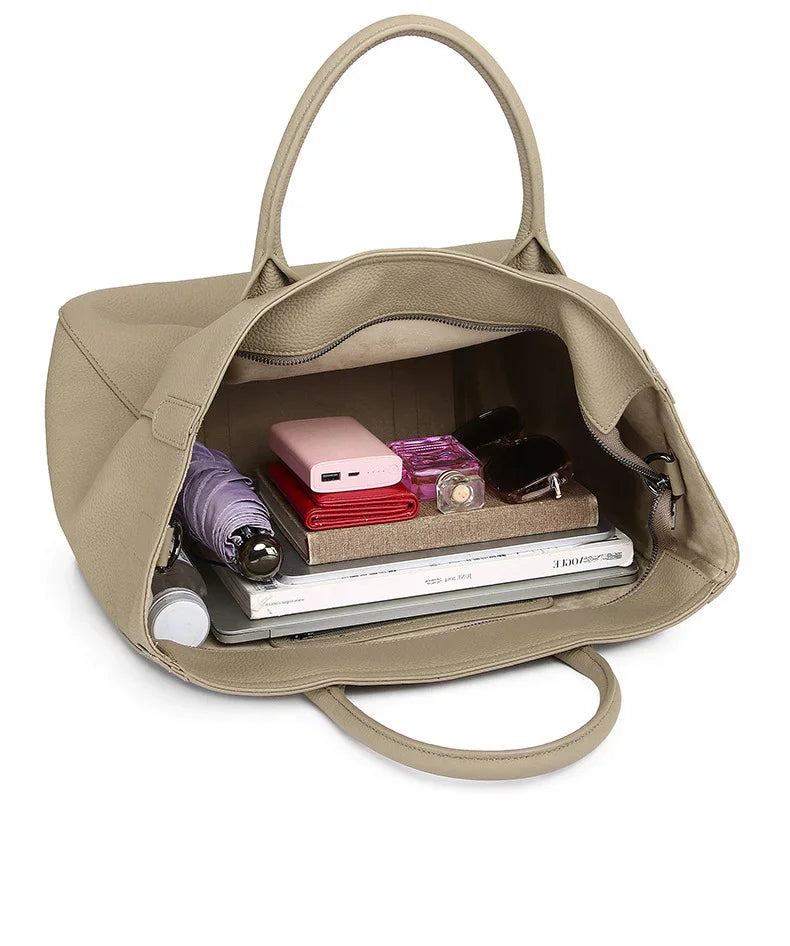 Beige leather tote bag open with books, wallet, umbrella, sunglasses, and essentials inside