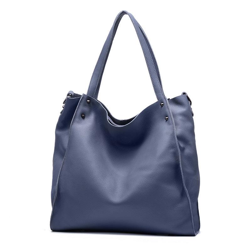 Large black leather tote bag with double handles and metal stud accents on a white background