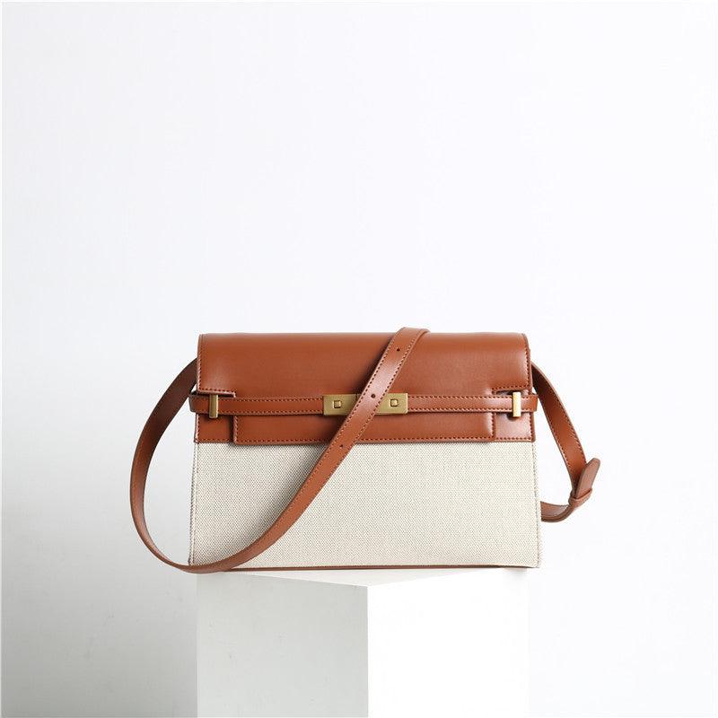 Minimalist leather and canvas crossbody bag with brown flap, gold hardware, and shoulder strap.