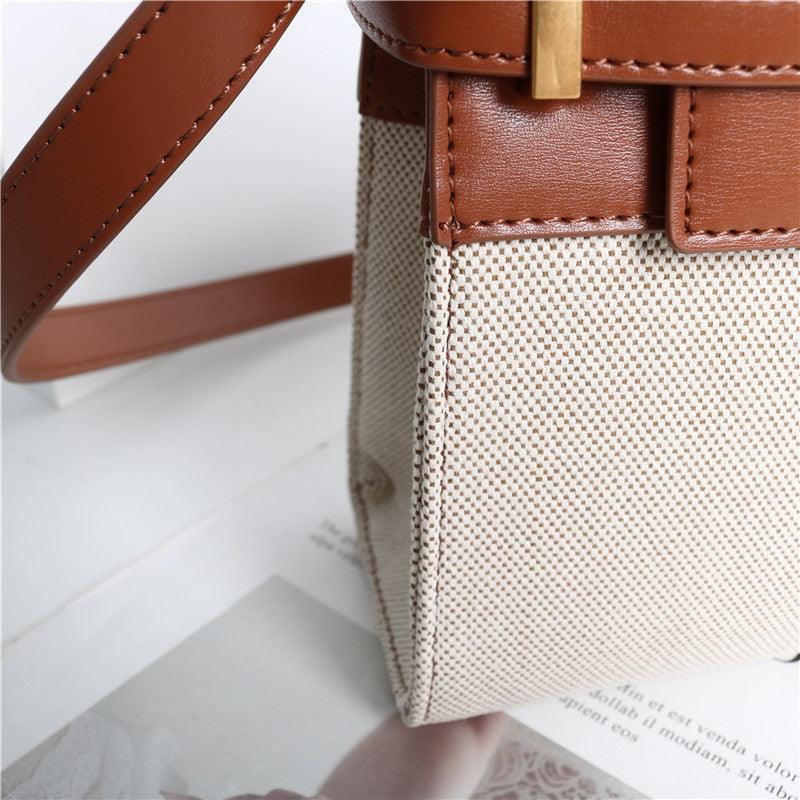 Minimalist crossbody bag with brown leather strap and beige textured fabric body