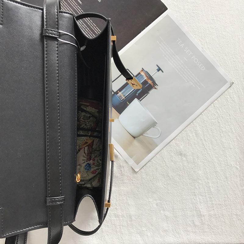 Minimalist black leather crossbody handbag open on table with floral lining visible