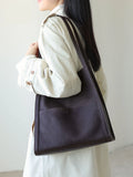 Woman wearing a minimalist brown grain cowhide leather tote bag on shoulder