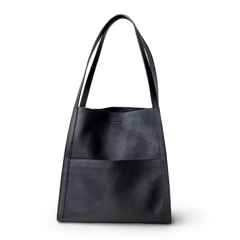 Black grain cowhide leather tote bag with minimalist design and front pocket on white background