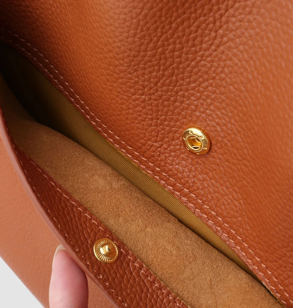 Close-up of brown grain cowhide leather tote bag interior with gold magnetic snap closure
