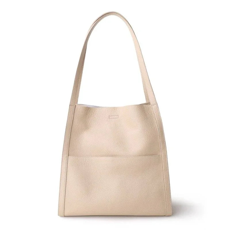 Minimalist beige cowhide leather tote bag with shoulder straps and front pocket on white background