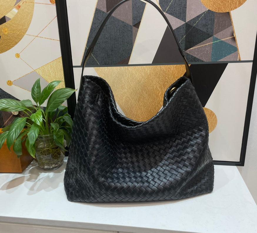 Black woven lambskin leather tote bag with shoulder strap on a white surface