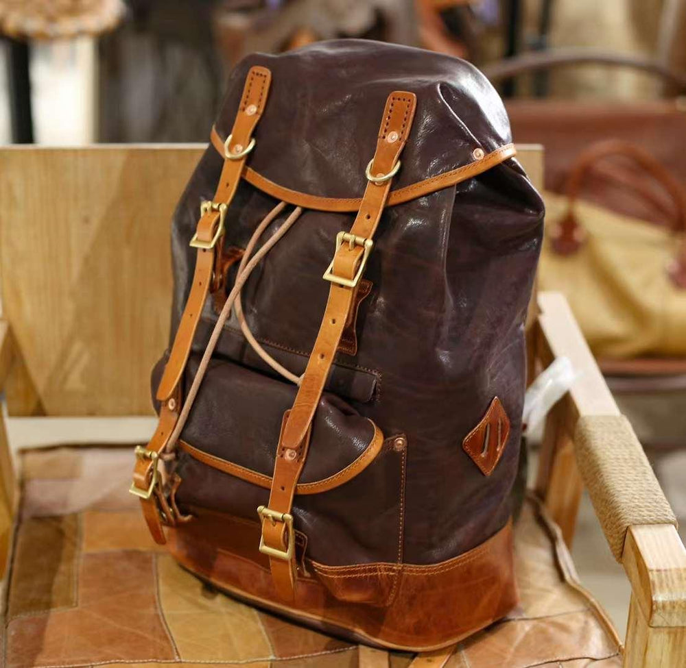Full grain cowhide leather military style backpack with brown straps on a chair