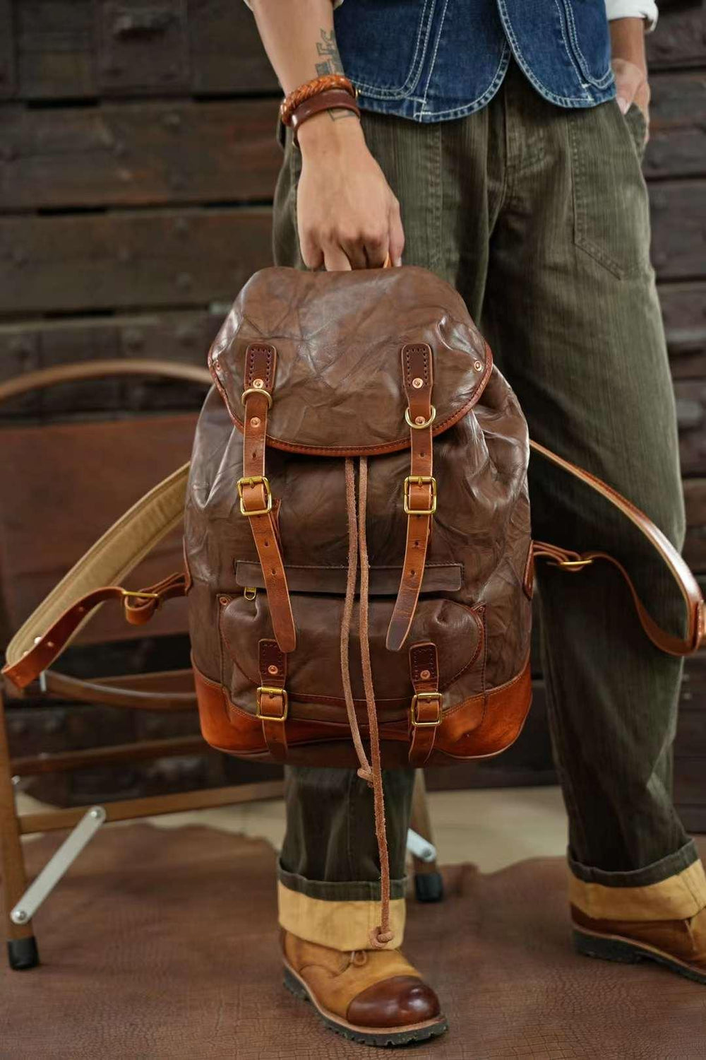 Vintage full grain cowhide leather backpack with buckles and drawstring, held by man
