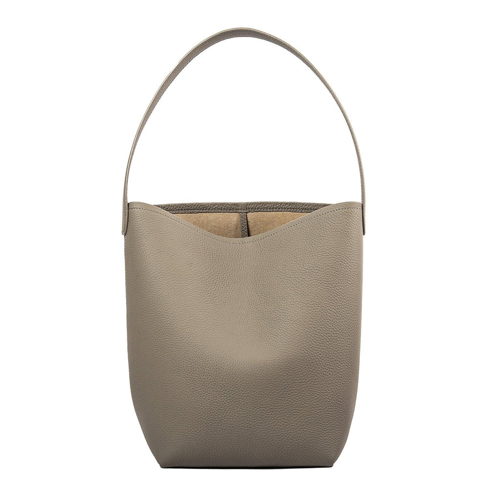 Minimalist large tan leather bucket bag with single shoulder strap on white background