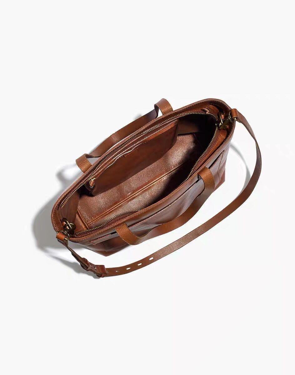 Tan full grain leather tote bag with shoulder strap and interior pocket, minimalist design