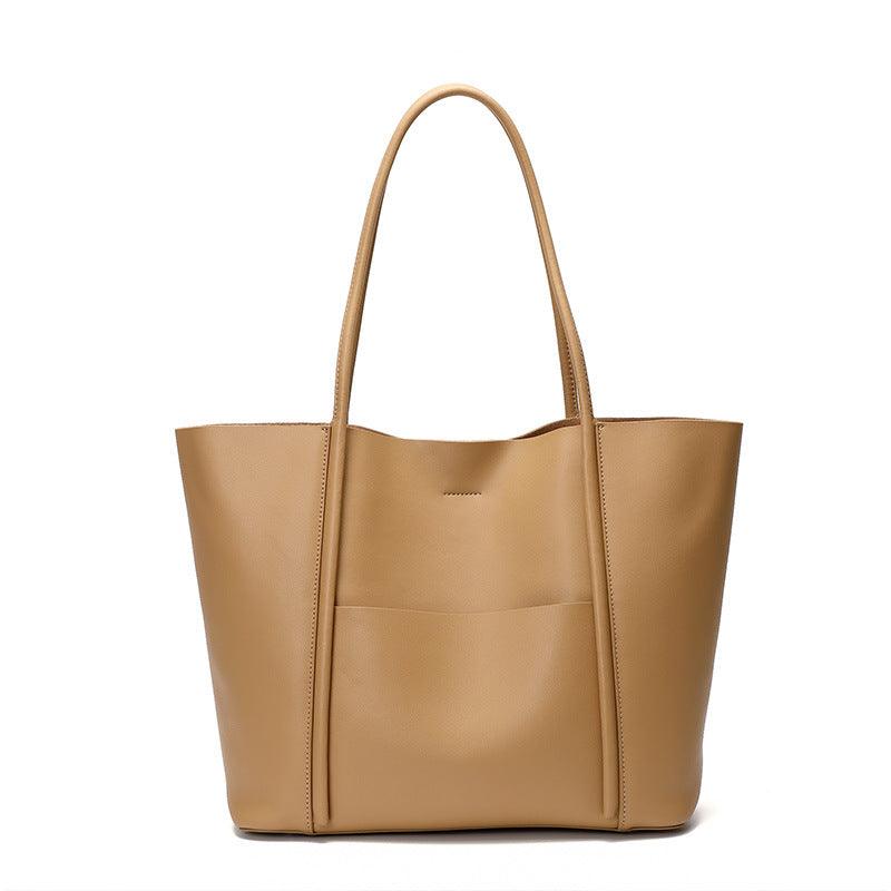 Minimalist beige genuine leather tote bag with top handles and front pocket on white background.
