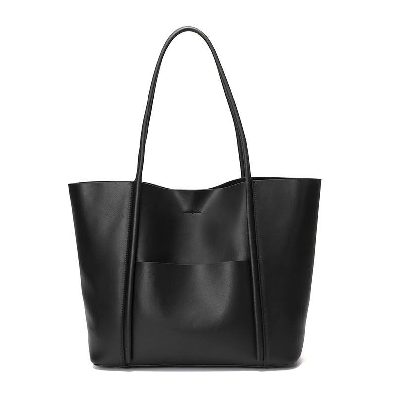 Minimalist black genuine leather tote bag with top handles and front pocket on white background
