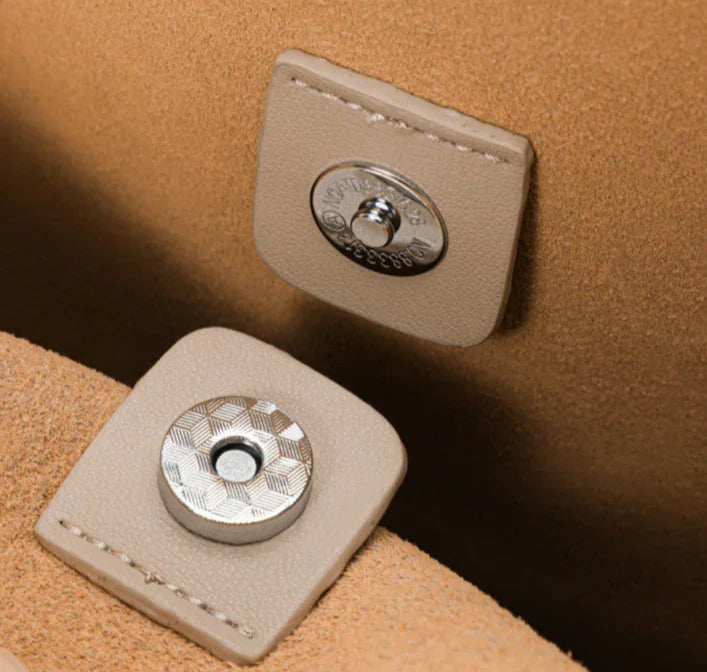 Close-up of beige leather handbag with metal magnetic snap closure
