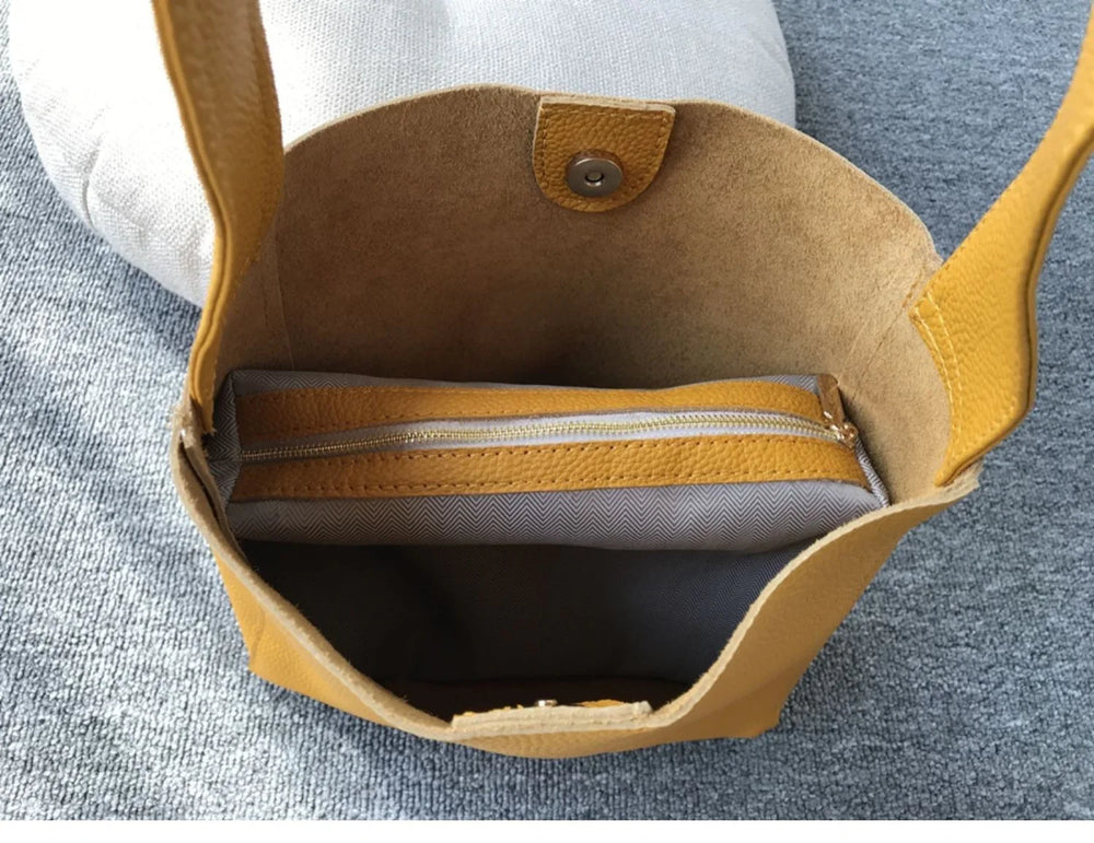 Minimalist pebbled cowhide leather bucket bag with wide shoulder strap and zippered pouch