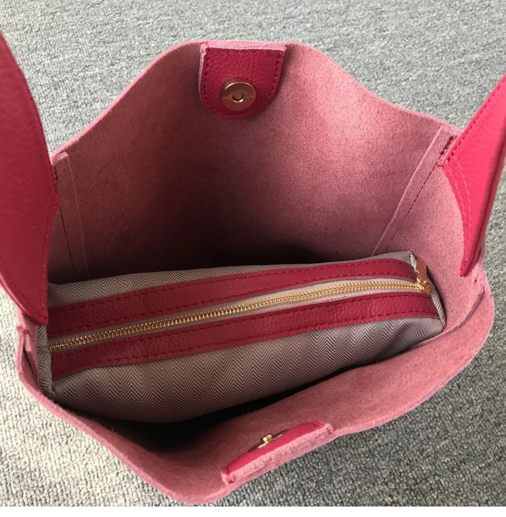 Open minimalist pink pebbled leather bucket bag with interior zip pouch and wide strap