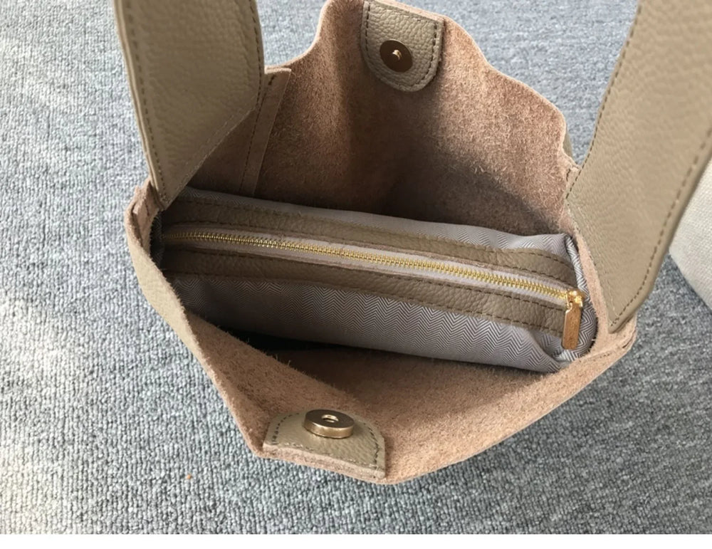 Interior of a beige pebbled cowhide leather bucket bag with wide strap and zippered pouch
