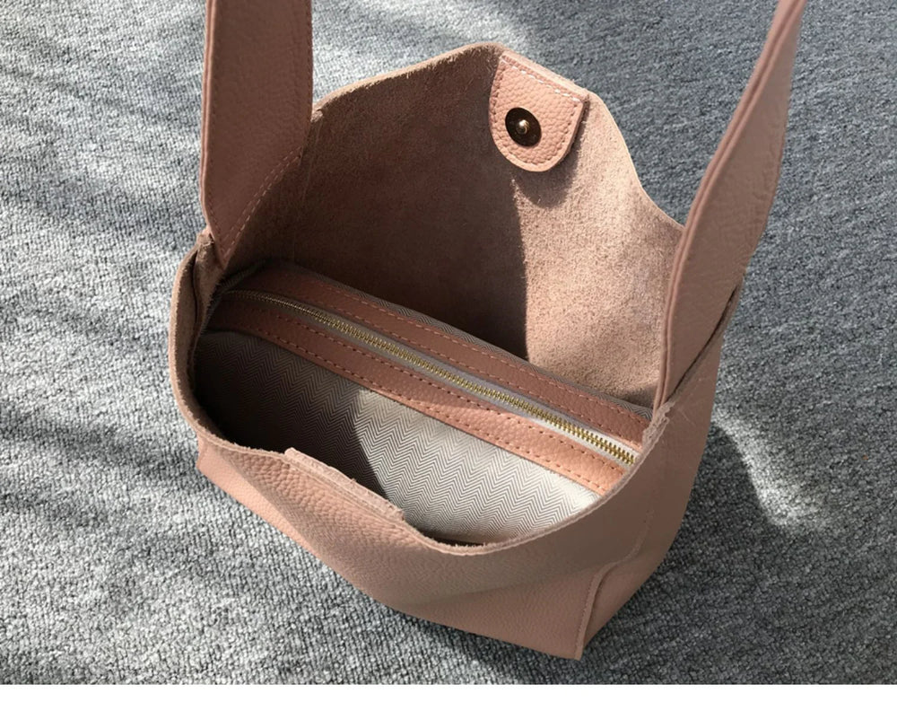 Minimalist pebbled cowhide leather bucket bag with wide shoulder strap and zip pouch