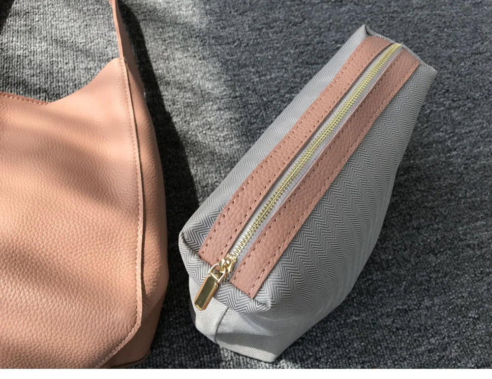 Minimalist pebbled cowhide leather bucket bag with wide shoulder strap and zippered pouch on fabric surface