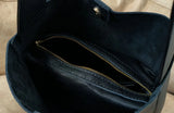 Interior of a black pebbled leather bucket bag with gold zipper pocket and suede lining