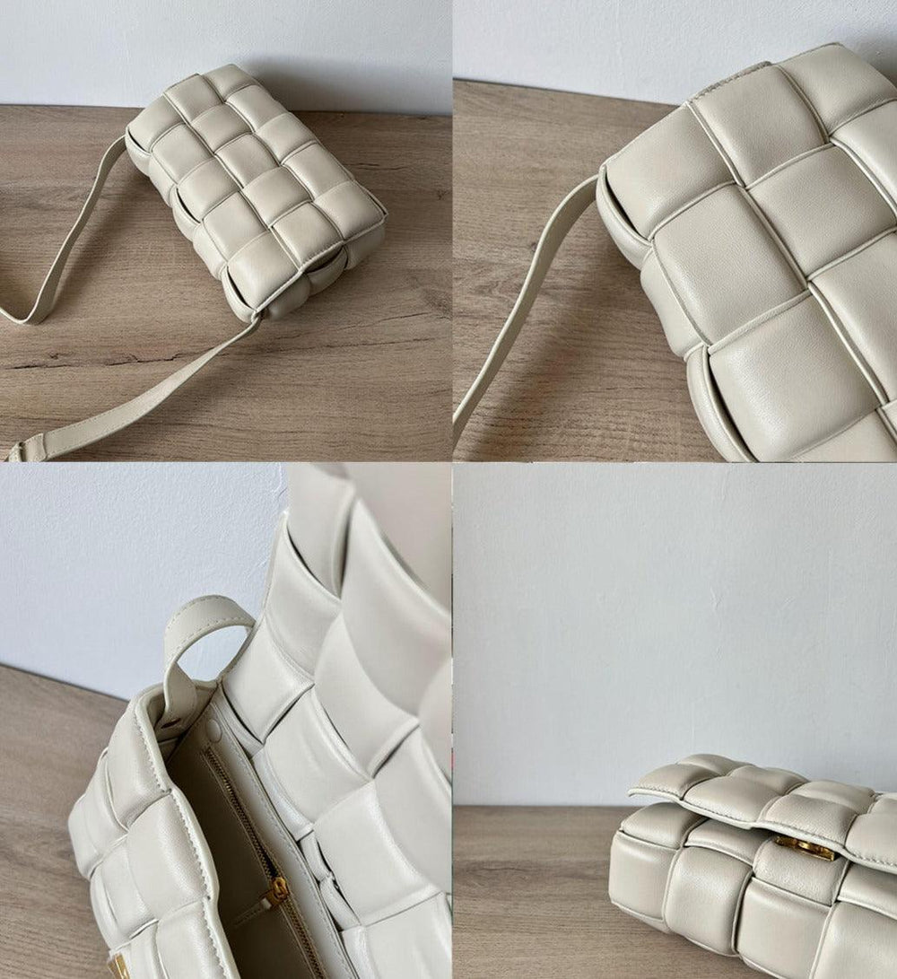 Cream woven leather crossbody bag with shoulder strap and gold zipper, on wooden surface