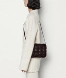 Woman wearing a cream wool coat and carrying a dark brown woven leather shoulder bag