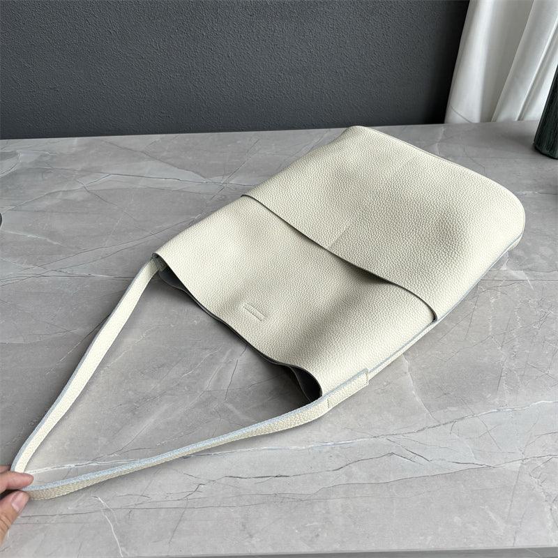 Ivory cowhide leather tote bag with two front pockets on marble surface