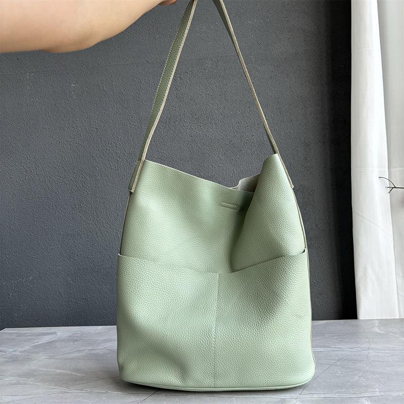 Sage green cowhide leather tote bag with two front pockets and minimalist bucket design