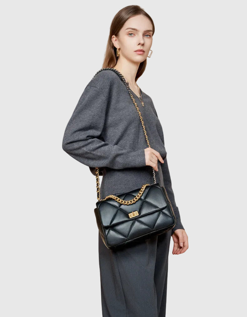 Woman with black quilted leather shoulder bag featuring gold chain strap and turn-lock clasp