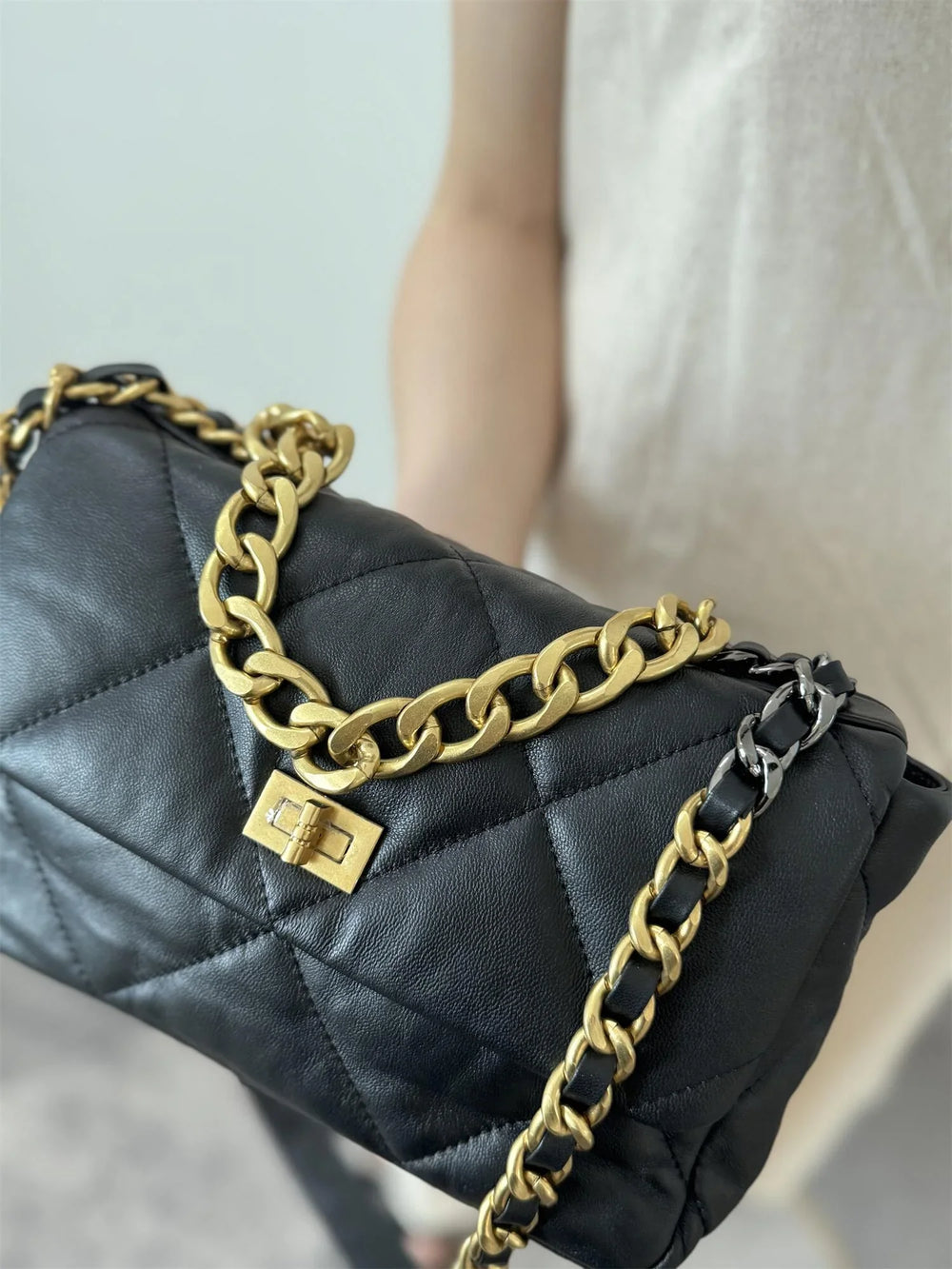 Black quilted leather flap bag with gold chain strap and turn-lock clasp, luxury shoulder bag