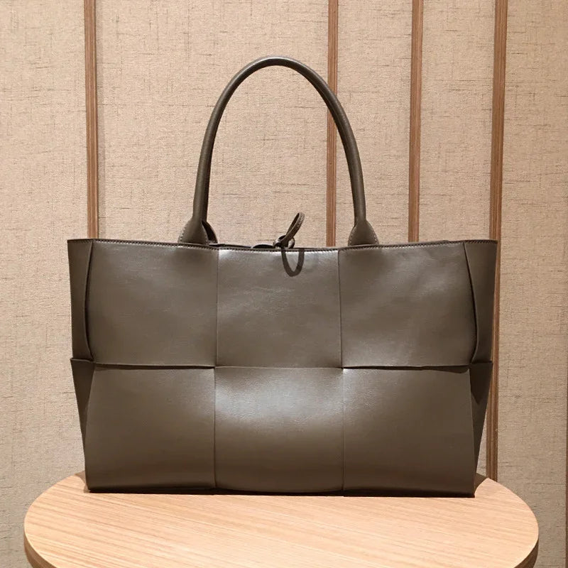 Quilted large leather tote bag with top handles, minimalist design on wooden table