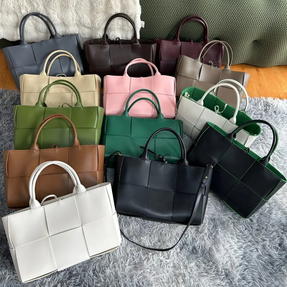 Assorted quilted leather tote bags with top handles in various colors on a textured rug.
