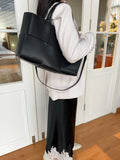 Woman wearing a black quilted leather tote bag with top handles and minimalist style