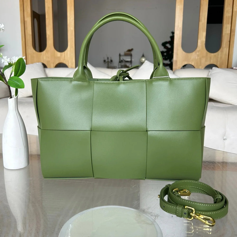 Green quilted leather tote bag with top handles and detachable shoulder strap on a table