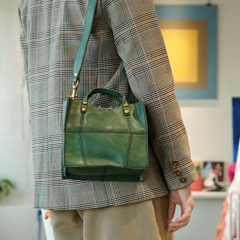 Green full grain leather small crossbody handbag with gold hardware, worn on shoulder