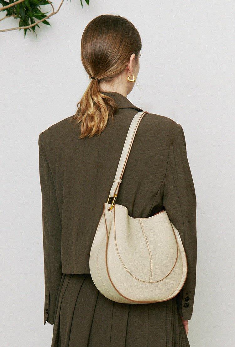 Woman wearing a cream smooth calfskin leather saddle bag with shoulder strap