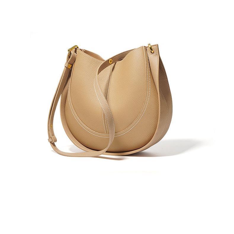 Smooth beige calfskin leather saddle bag with adjustable shoulder strap on white background