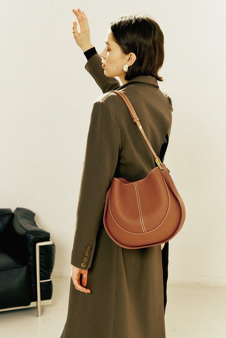 Woman in brown coat with a smooth calfskin leather saddle bag shoulder pouch