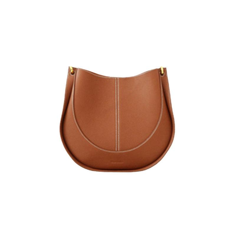 Smooth brown calfskin leather saddle bag with curved shape and visible stitching on white background
