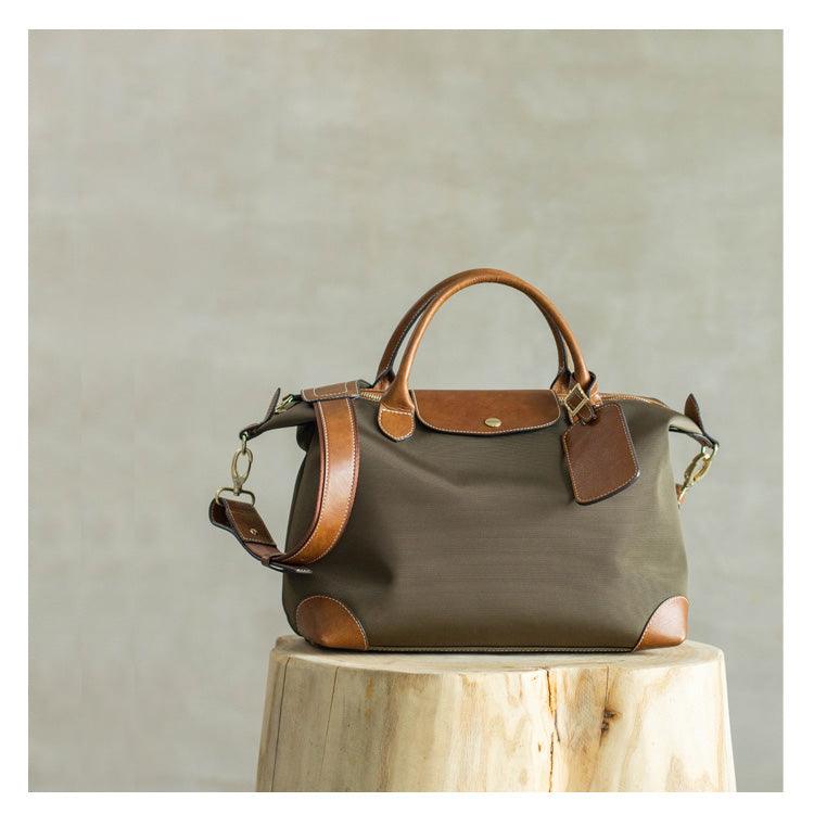 Olive green nylon and brown cowhide leather tote bag with handles and shoulder strap on wooden stool