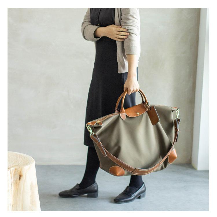 Woman holding large olive waterproof nylon and cowhide weekend tote bag with leather trim