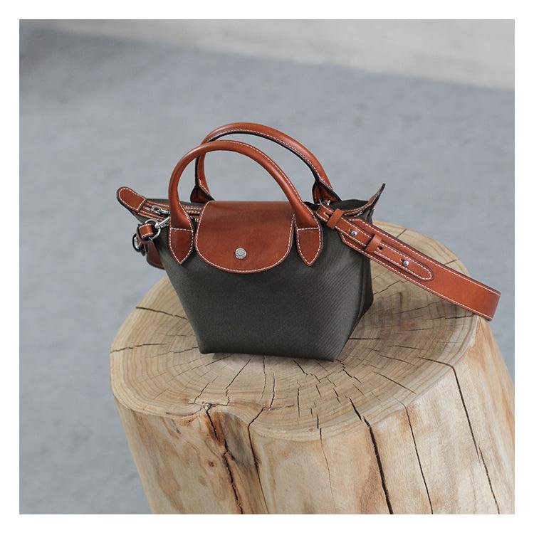 Waterproof nylon and cowhide tote bag with brown leather handles and strap on wood stump